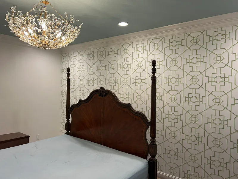 This elegant bedroom features a sophisticated geometric lattice wallpaper in soft sage green on a crisp white or light neutral background. The intricate, repeating pattern of interlocking octagons, squares, and angled lines creates a timeless, architectural trellis-like design with clean symmetry and subtle depth. Perfect for adding refined structure and understated luxury to bedrooms, this versatile motif brings a modern yet classic feel—evoking subtle chinoiserie or garden trellis influences while remaining airy and serene. (Installed to beautiful effect in a local Anderson-area home—ideal for creating calm, polished spaces!)