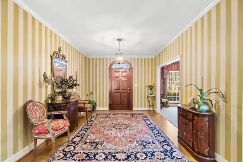 This elegant entryway is beautifully defined by classic vertical striped wallpaper in warm golden tones. The clean, evenly spaced stripes add height and sophistication to the room, creating a timeless backdrop that brightens the space while complementing the home’s traditional architecture. Professionally installed wallpaper like this brings precision, symmetry, and a polished finish that paint simply can’t achieve, transforming an ordinary foyer into a refined and welcoming first impression.